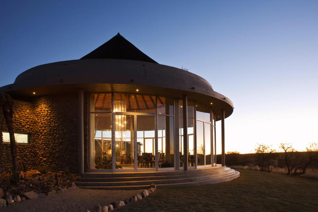 a building with a large window with the sunset in the background at Naankuse Lodge in Windhoek