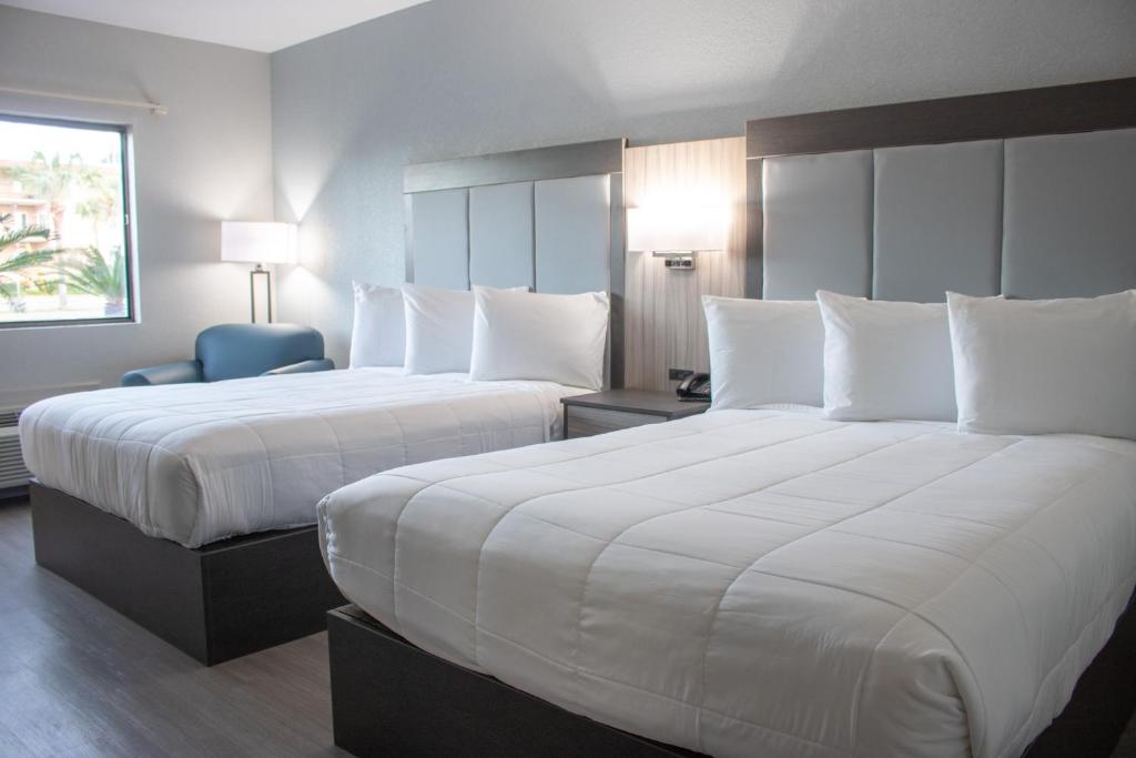 ein Hotelzimmer mit 2 Betten und weißen Kissen in der Unterkunft Admiral's Inn on Tybee Island in Tybee Island