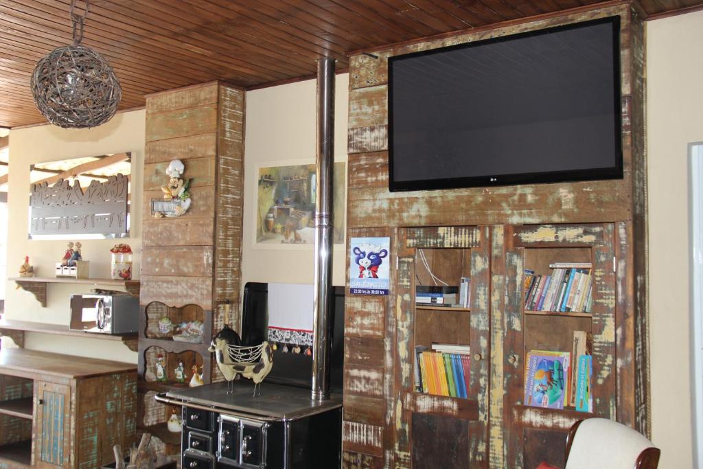 uma sala de estar com televisão numa parede de tijolos em Pousada Casa do Luiggi em Penha