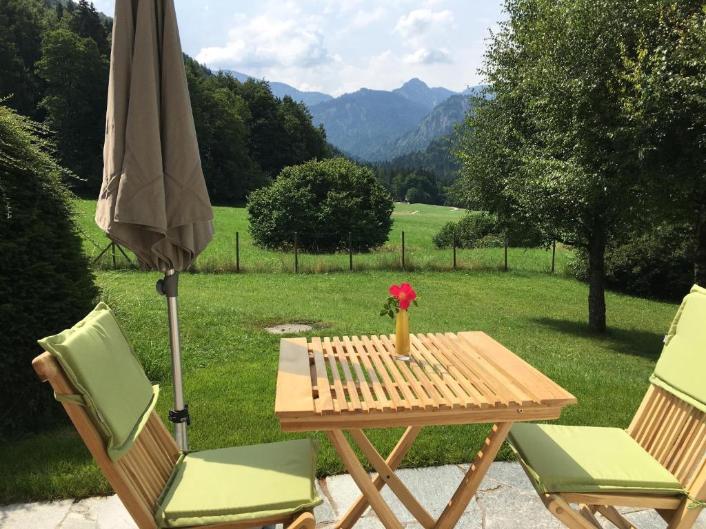 una mesa con un jarrón de flores y una sombrilla en Bergblick Riedlern - Ferienwohnung en Kreuth