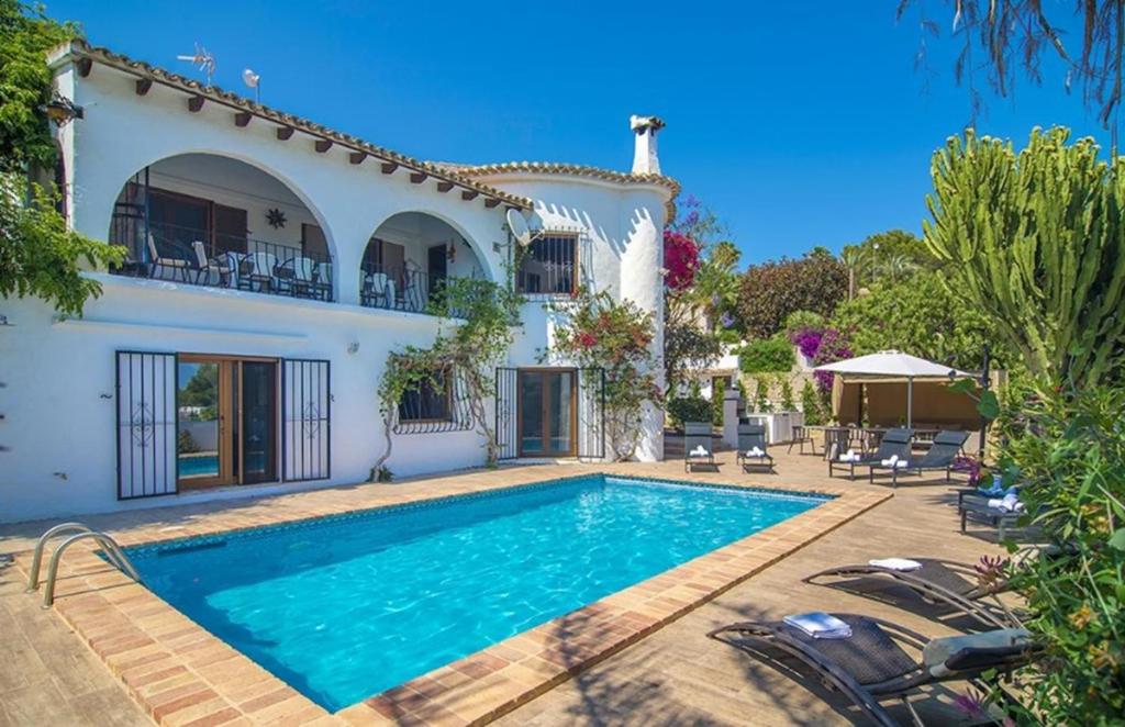 a villa with a swimming pool in front of a house at Villas Guzman - Amandiere in Benissa