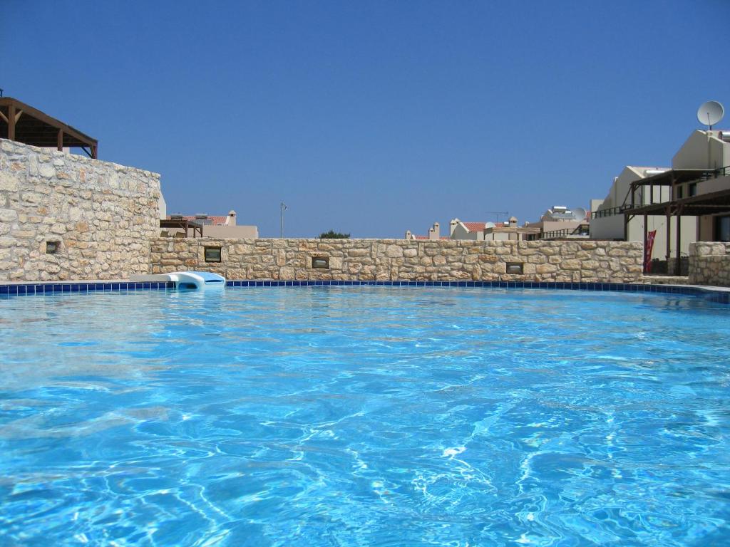 una piscina de agua azul y una pared de piedra en Villa Oscania, en Georgioupolis