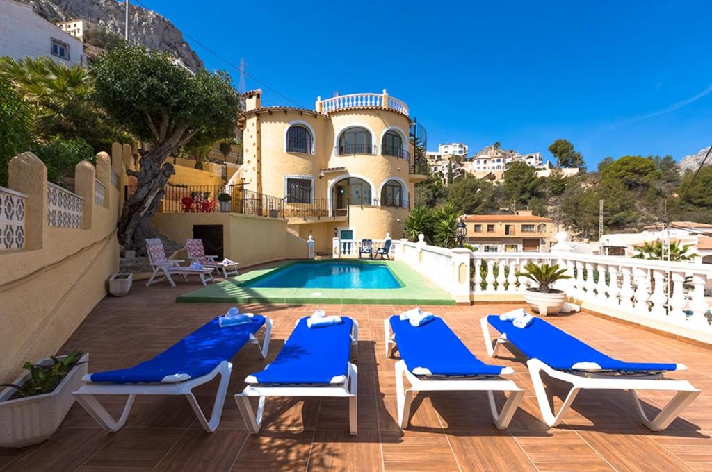 une villa avec une piscine et des chaises longues bleues dans l'établissement Villas Guzman - Antonio, à Calp
