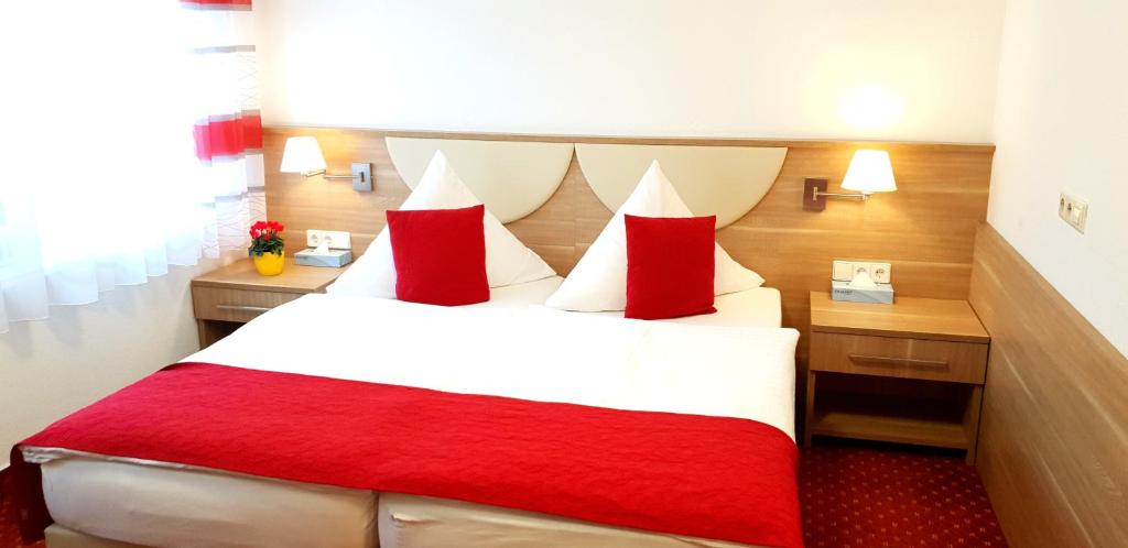 a hotel room with a large bed with red pillows at Aparthotel Wangener Landhaus in Stuttgart