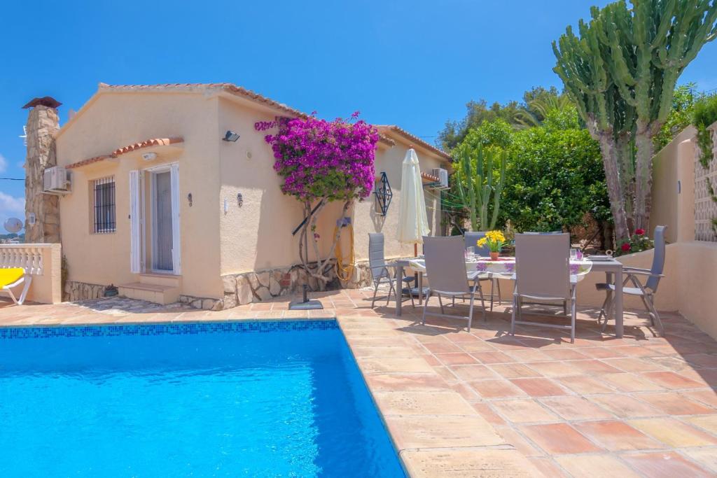 a villa with a swimming pool and a table and chairs at Villas Guzman - Bibiane in Benissa