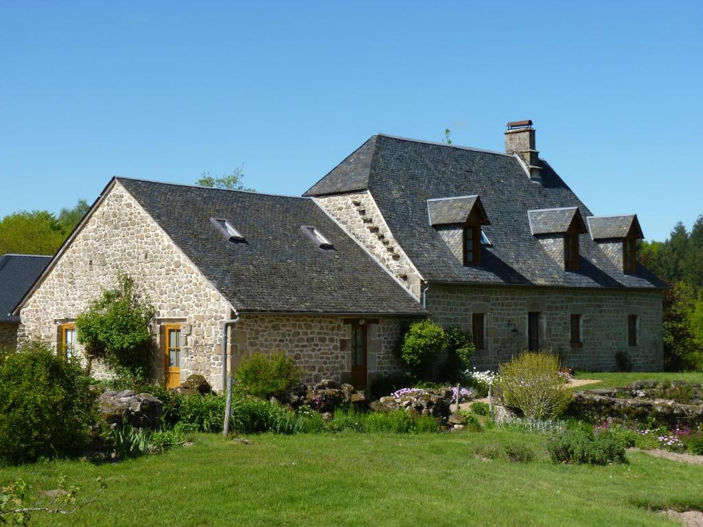 une grande maison en pierre avec un toit en gambrel dans l'établissement La Ferme de Leix, à Clergoux
