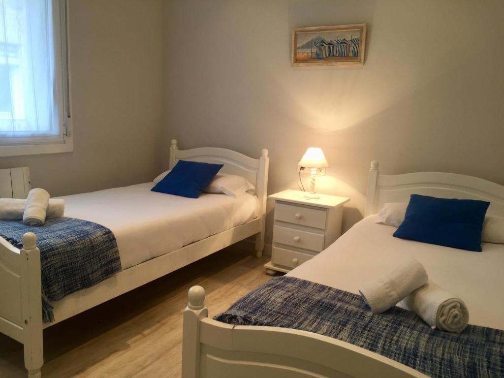 two beds in a small room with blue pillows at Easo amplio y funcional cerca de la playa. in San Sebastián