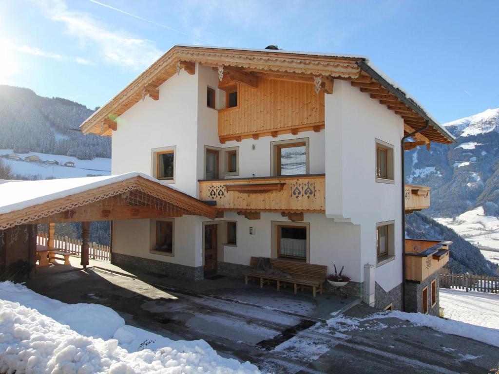 ゲルロスベルクにあるWooden Chalet in Zell am Ziller with Terrace and Viewsの雪の中のベンチ付きの建物