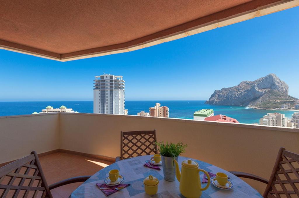 a table on a balcony with a view of the ocean at Villas Guzman - Apartamento Coral Beach in Calpe