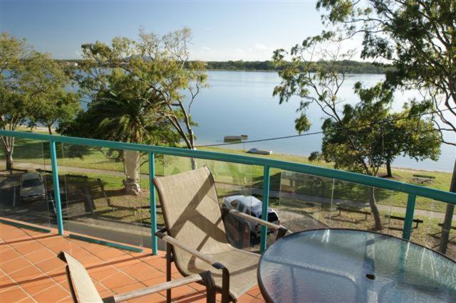 een tafel en een stoel op een balkon met uitzicht op een meer bij The Esplanade Riverview Holiday Apartments in Maroochydore