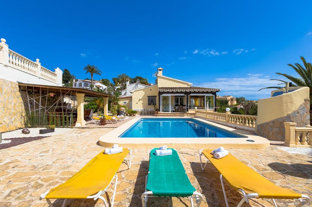a swimming pool with two lounge chairs and a house at Villas Guzman - Kismet in Moraira