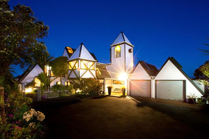 una gran casa blanca con una torre de reloj por la noche en Tivoli Homestay, en New Plymouth