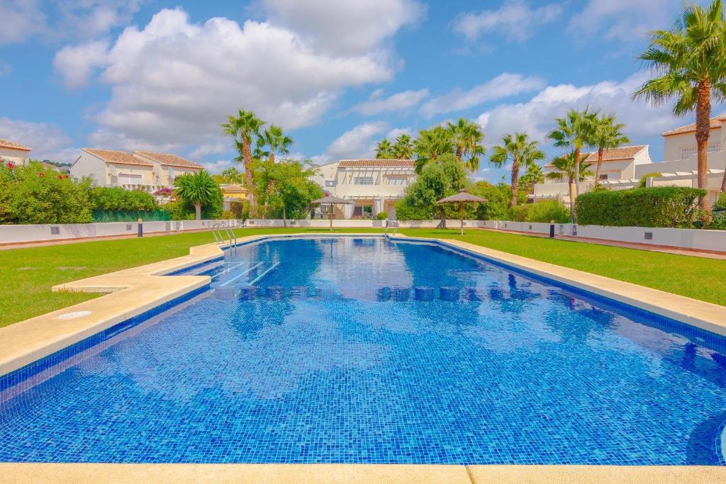 duży basen na dziedzińcu z palmami w obiekcie Villas Guzman Margaret w mieście Calpe
