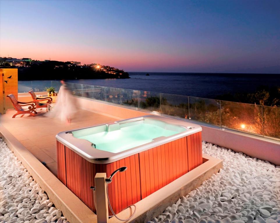 a hot tub on a deck with the ocean in the background at Out Of The Blue Resort & Spa in Agia Pelagia