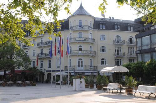 un grand bâtiment blanc avec drapeaux devant lui dans l'établissement Hotel Haus Reichert, à Baden-Baden