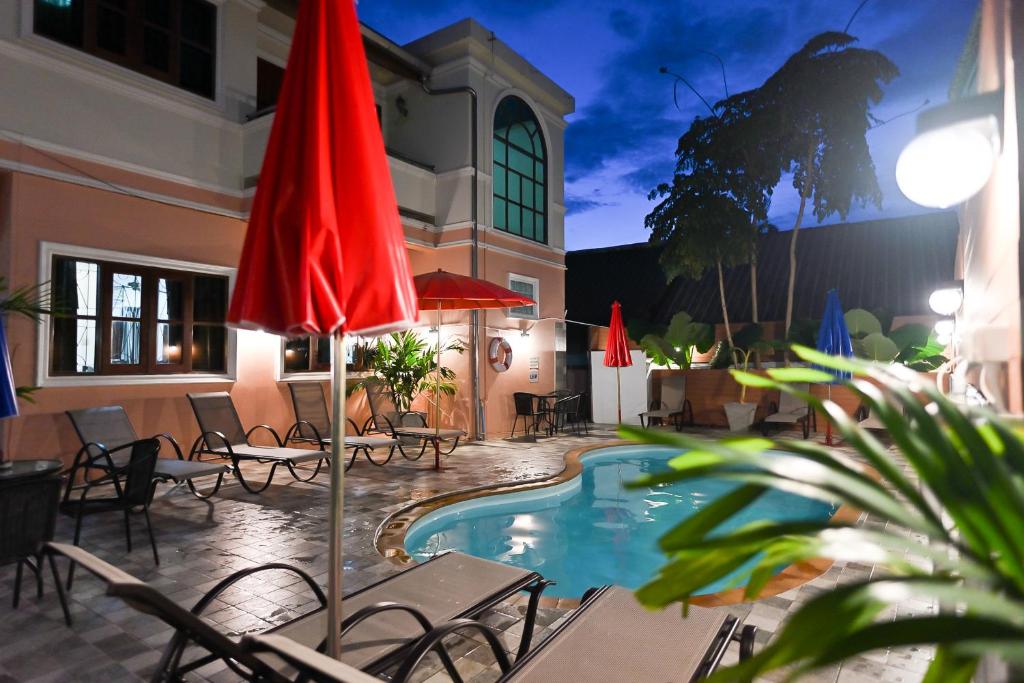 a patio with a pool and chairs and a red umbrella at The Villa Residences Resort in Patong Beach