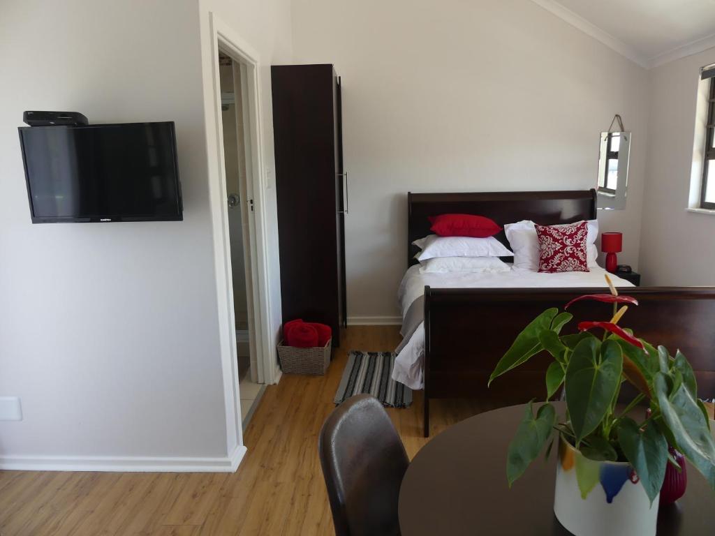 a bedroom with a bed and a table with a plant at Rose and Ale Self Catering Units in Gonubie