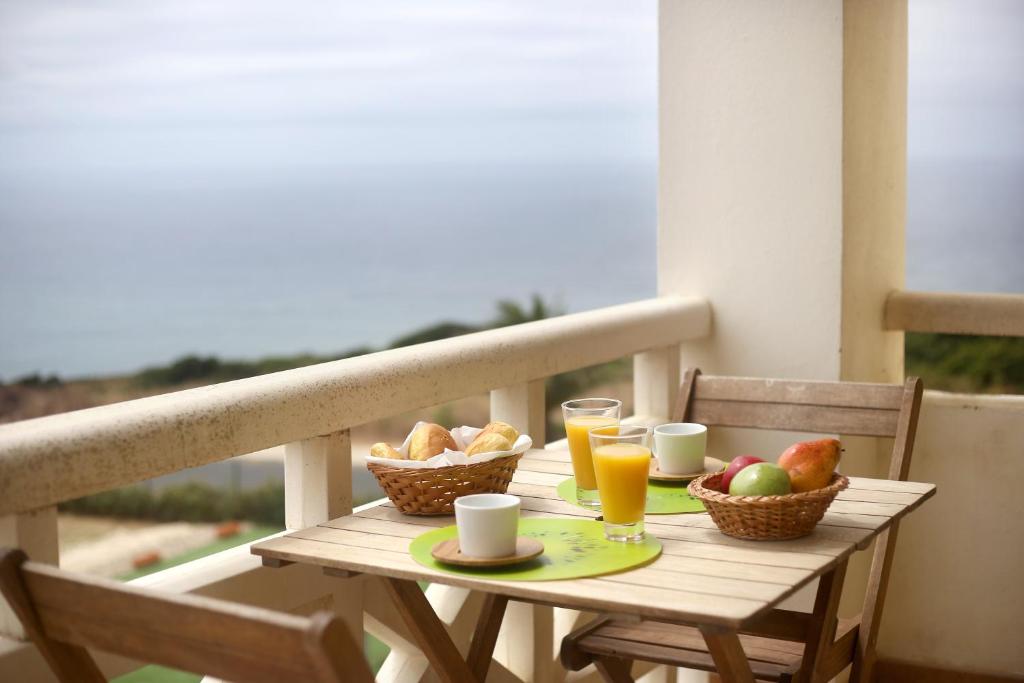 einen Holztisch mit Obstkorb und Getränken auf dem Balkon in der Unterkunft Like-home Blue Dreams in Ericeira