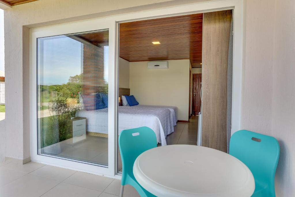 a room with a bed and a table and a window at Pousada Ilha Faceira in Florianópolis