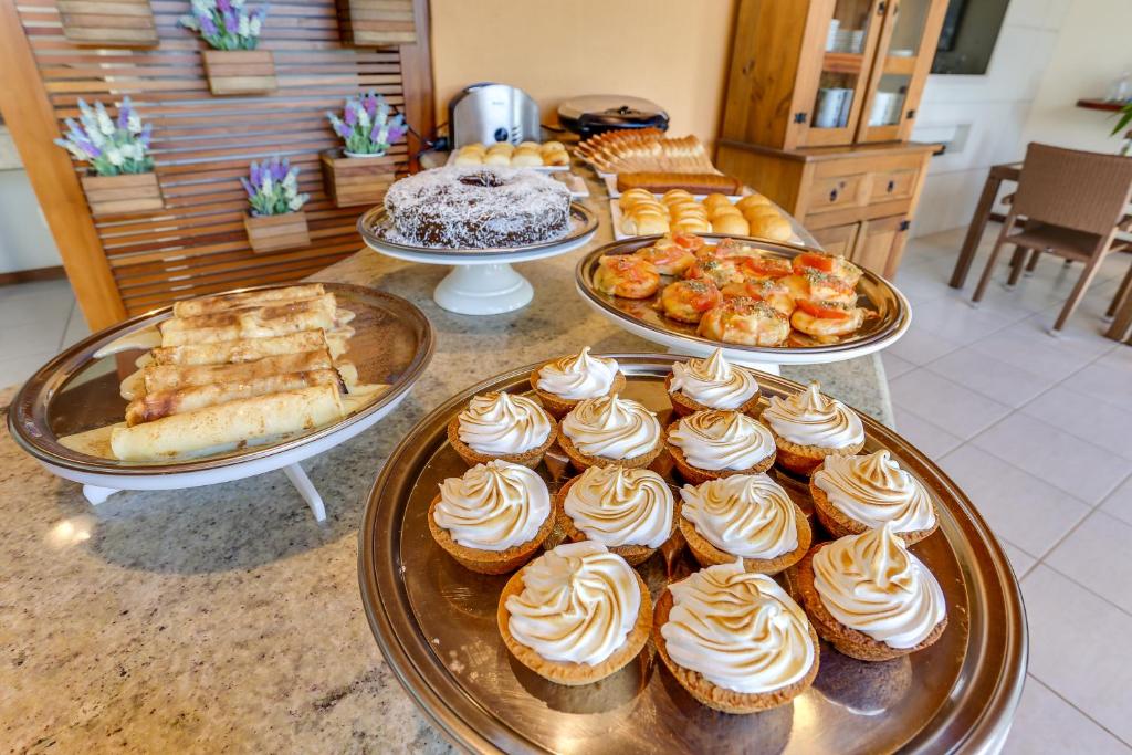 a buffet with several trays of cupcakes and other desserts at Pousada Ilha Faceira in Florianópolis