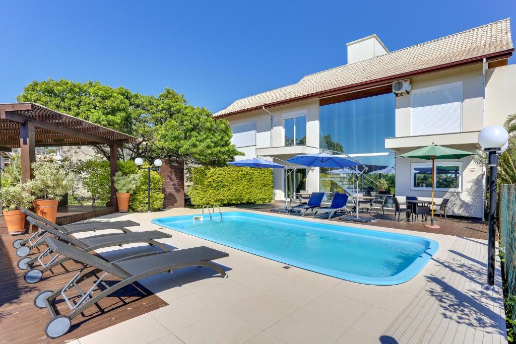 a swimming pool with lounge chairs and a house at Pousada Ilha Faceira in Florianópolis