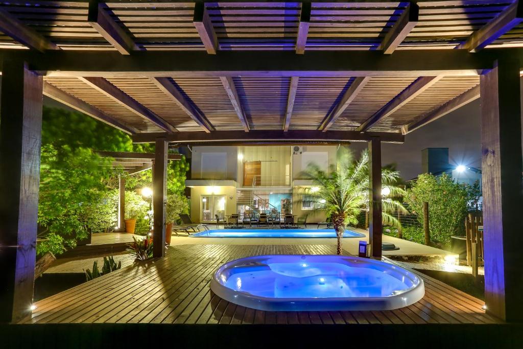 a large hot tub on a deck with a house at Pousada Ilha Faceira in Florianópolis