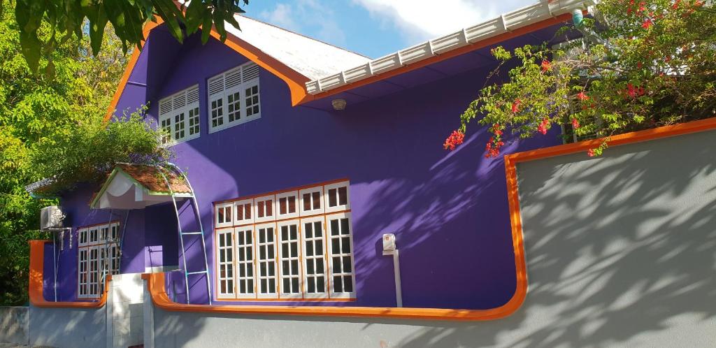 ein lila Haus mit einer Reflexion eines Gebäudes in der Unterkunft Fuvahmulah inn in Fuvahmulah