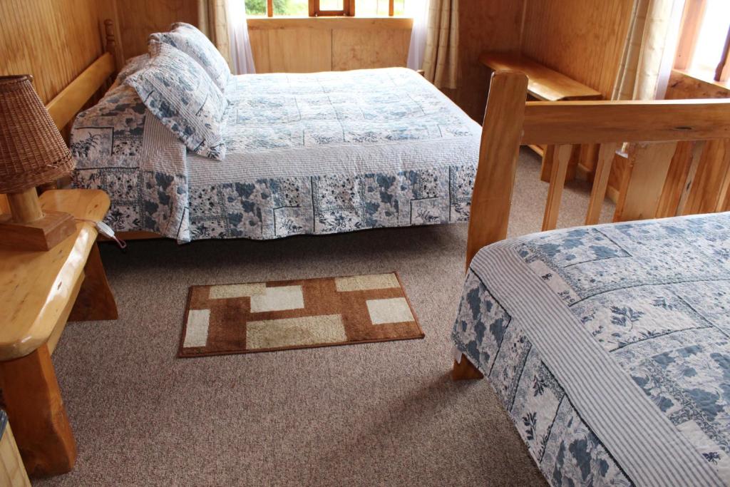 a room with three beds and a table and chairs at Los Mañíos Del Queulat Puyuhuapi in Puerto Puyuhuapi
