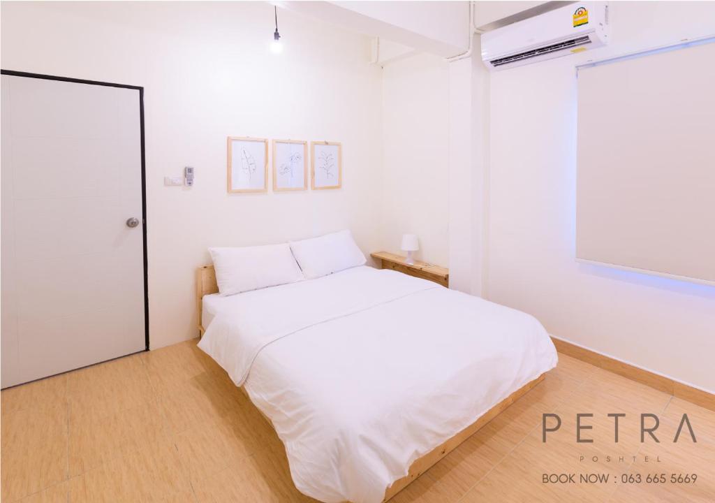un letto bianco in una camera bianca con finestra di Petra Poshtel Donmuang a Bangkok