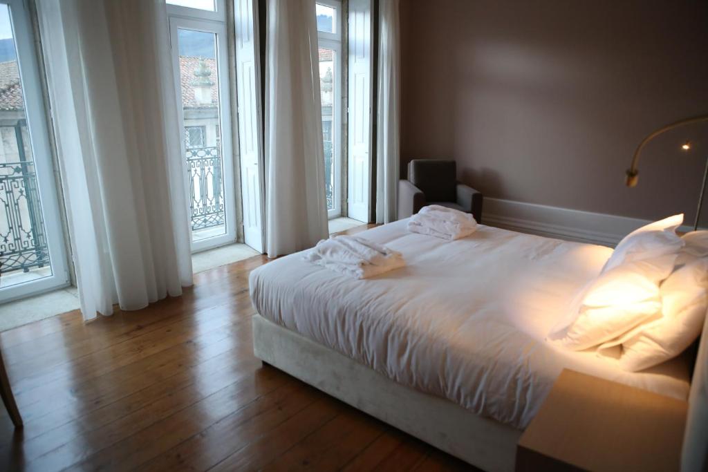 a bedroom with a white bed and large windows at Muralha Charm House in Lamego