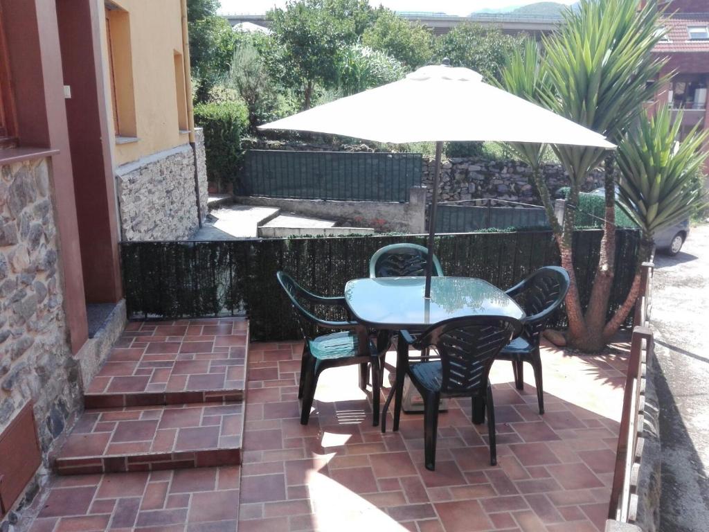 a table and chairs with an umbrella on a patio at Casa Fuente el vache in Campomanes