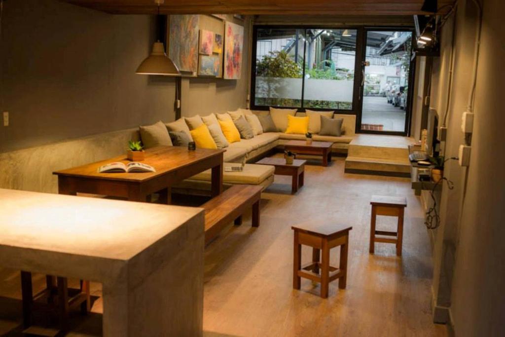 In a Box Hostel في بانكوك: غرفة معيشة مع أريكة وطاولة وكراسي