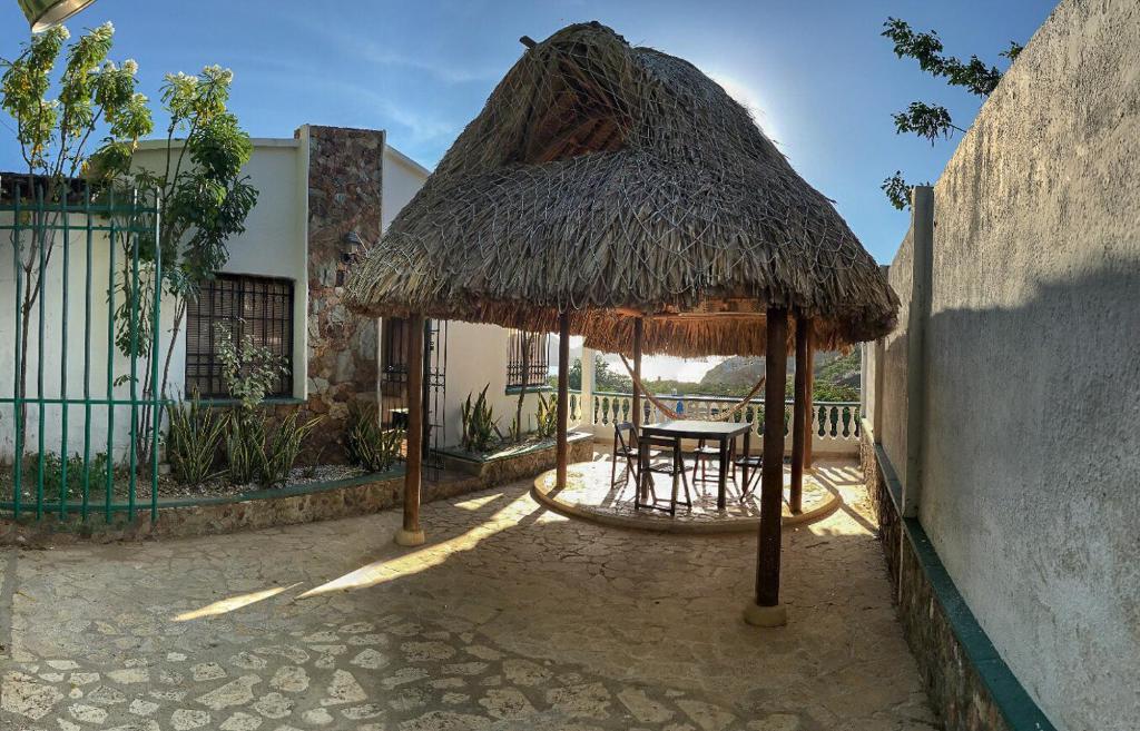 a patio with a table and a straw umbrella at Casa Mirador del Cielo in Taganga