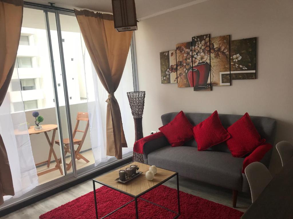 sala de estar con sofá gris y almohadas rojas en Departamento Pacífico III La Serena, en La Serena