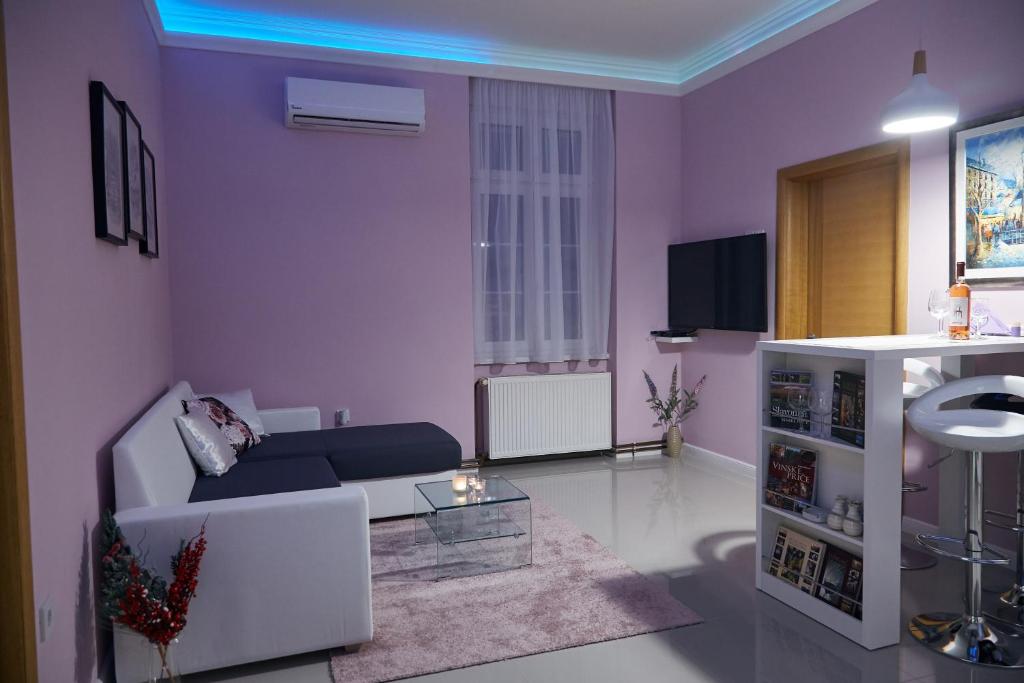 a living room with purple walls and a white couch at Station in Osijek