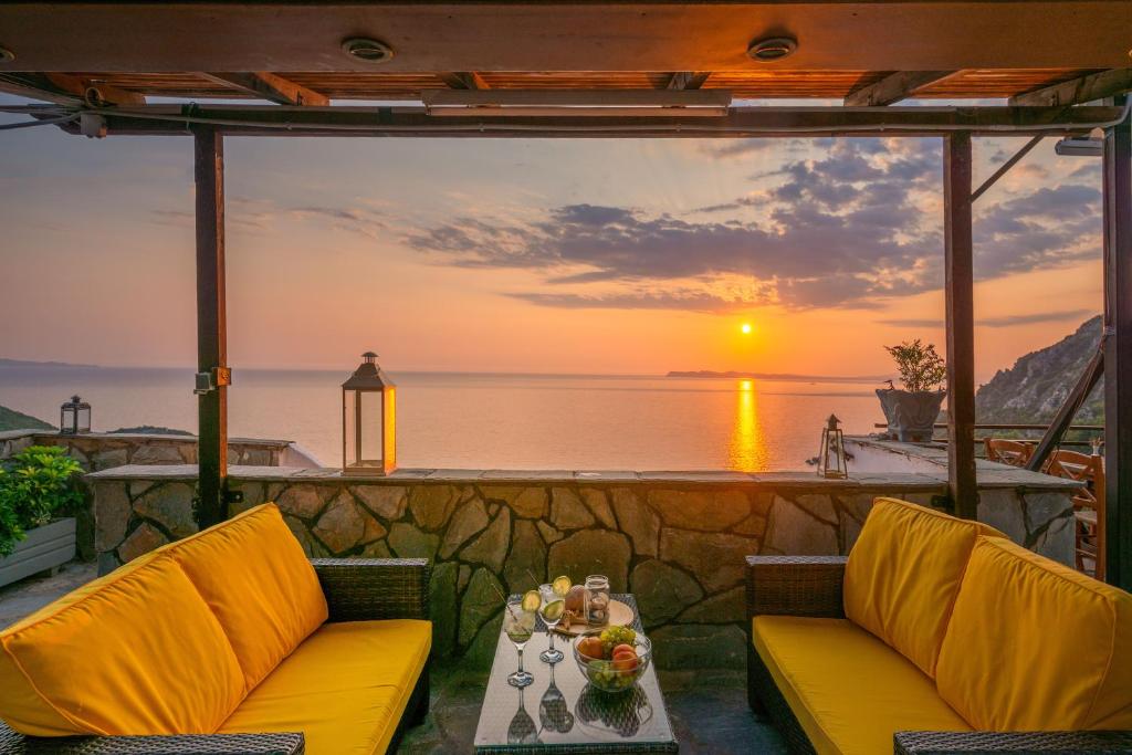 a patio with two chairs and a table with a sunset at Arilla Beach Hotel in Perdika