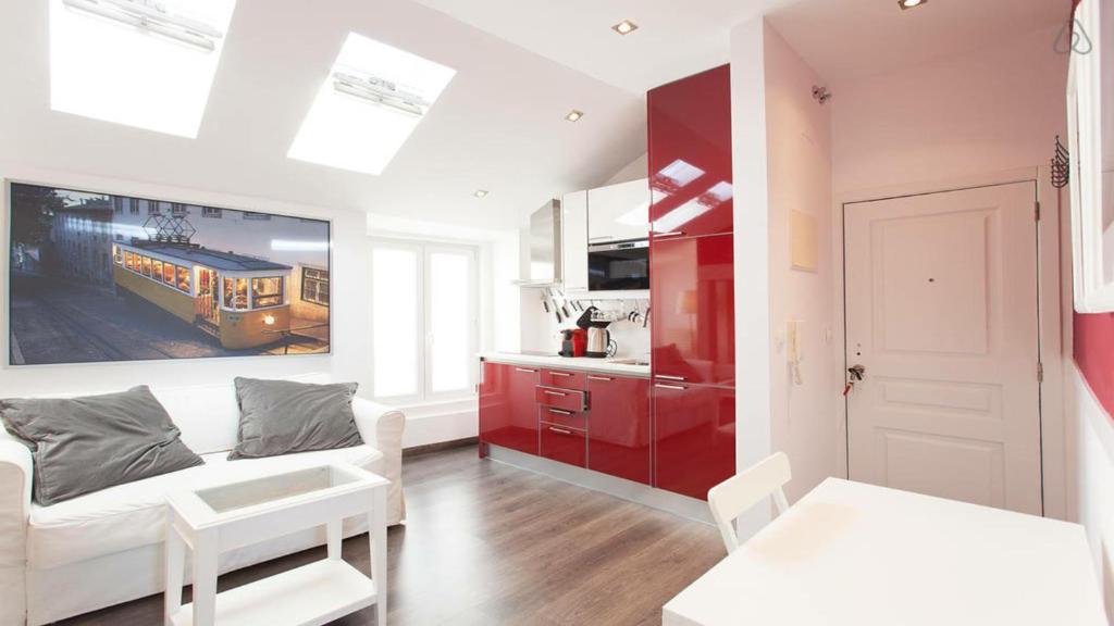 a living room with a white couch and a red kitchen at Boutique Apartments Lisboa in Lisbon