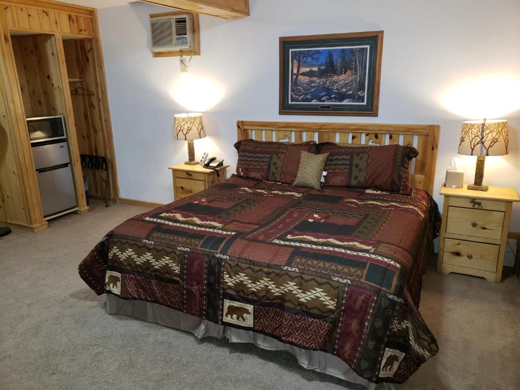 um quarto com uma cama e duas mesas de cabeceira com candeeiros em Willard Munger Inn em Duluth
