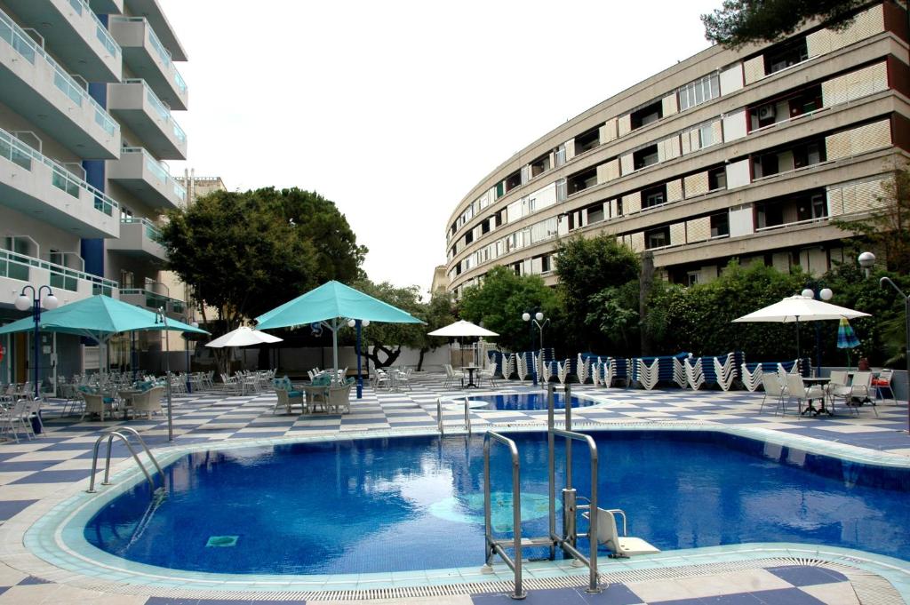a swimming pool with chairs and umbrellas next to a building at Santa Monica Playa in Salou