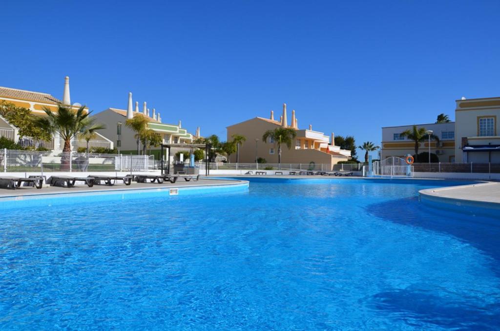 a large swimming pool with blue water and buildings at São Rafael Townhouse By OCvillas in Albufeira