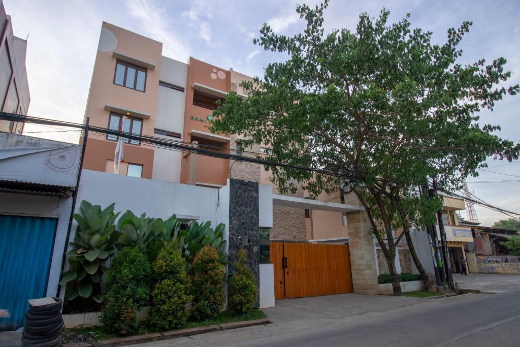 a building with a wooden gate and a tree at RedDoorz Plus @ CBD Bintaro in Peladen