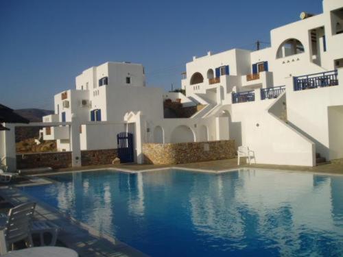 a swimming pool in front of some white buildings at Rita's Place Hotel in Ios Chora