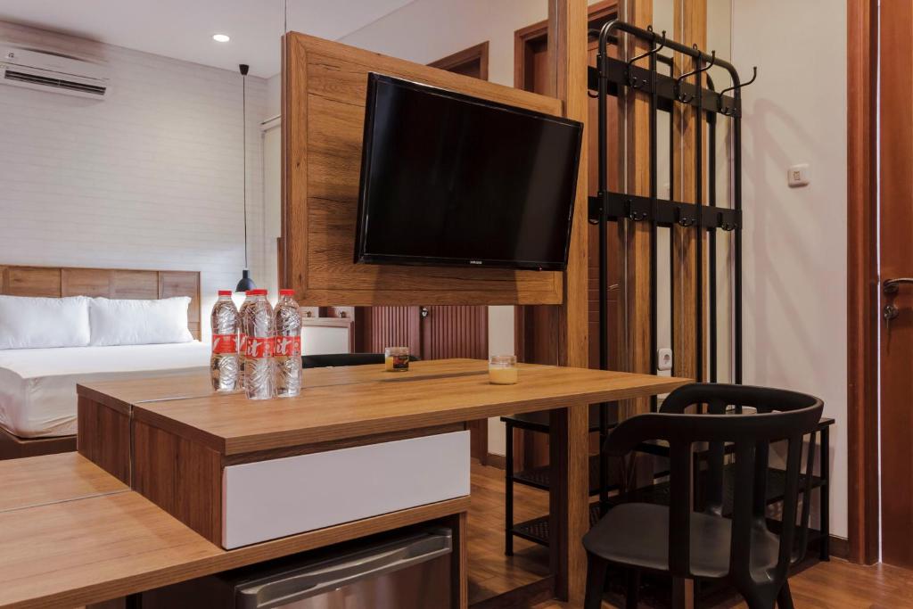 un soggiorno con scrivania e TV a parete di RedDoorz Plus @ CBD Bintaro a Peladen