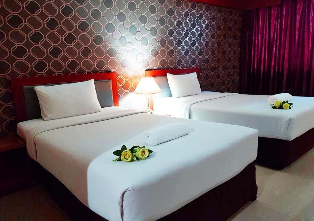 two beds in a hotel room with flowers on them at JP Emerald Hotel in Yasothon