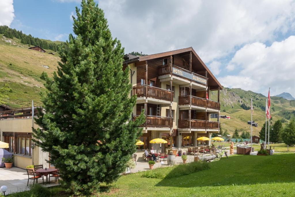 a large building with a tree in front of it at Hotel Restaurant Silbersand in Riederalp