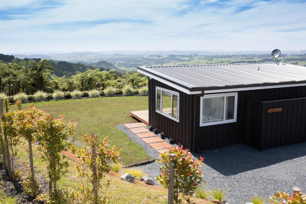 a black tiny house with a view of a garden at Skylark Lodge in Okaihau