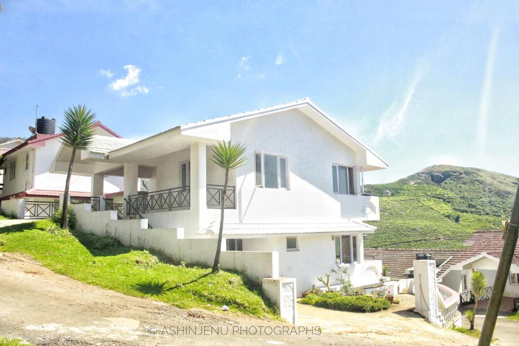 a white house with palm trees in front of it at Mist Resorts Ooty in Ooty