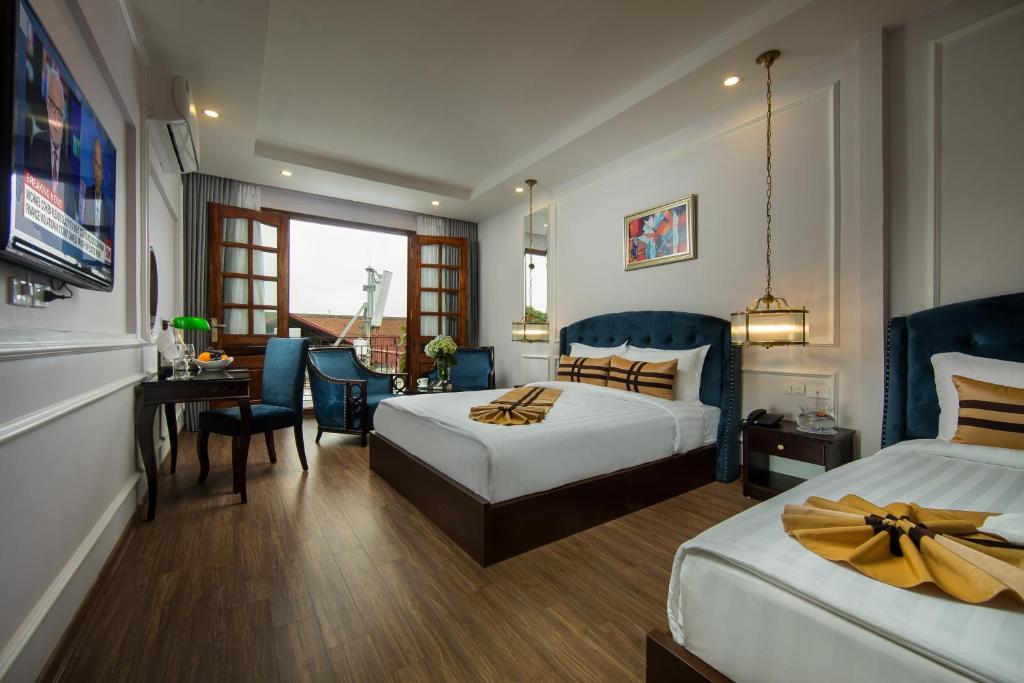 a hotel room with two beds and a dining room at S Central Hotel and Spa in Hanoi