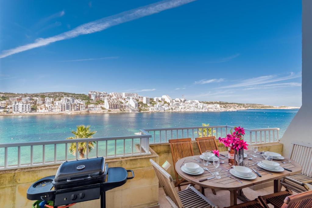 a balcony with a table and a view of the water at Blue Harbour Seafront 3 bedroom apartment, with spectacular sea views from terrace - by Getawaysmalta in St. Paul's Bay