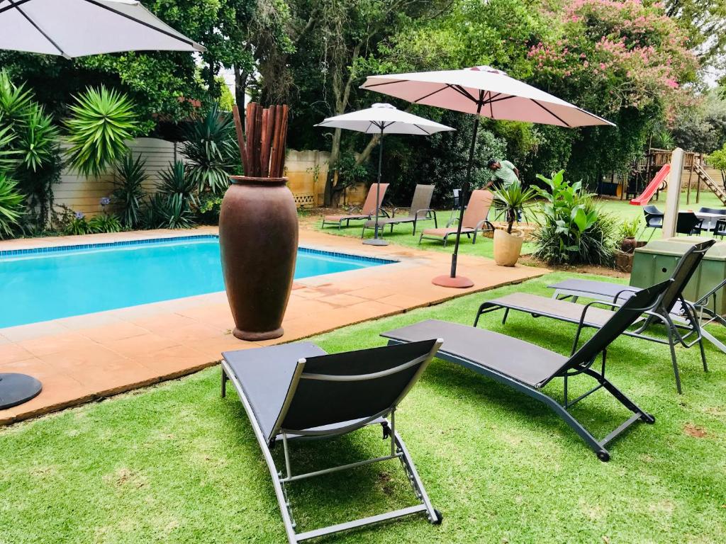 a group of chairs and a vase next to a pool at Aerotropolis Guest Lodge in Kempton Park